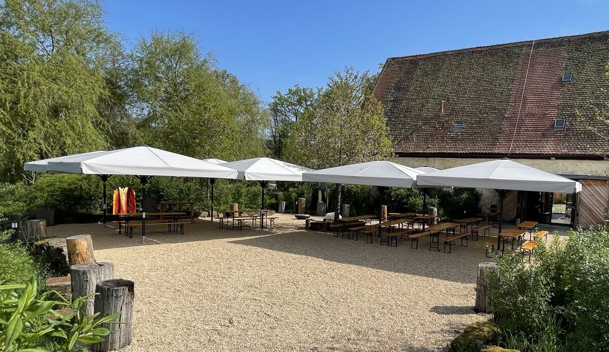 Entfernter Blick auf den Biergarten mit Schirmen, blauer Himmel