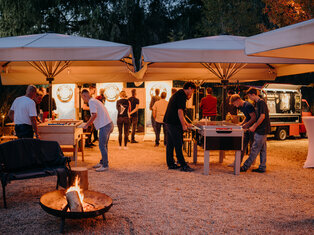 Blick in den Biergarten mit Feuerschale und Tischkicker in der Dämmerung