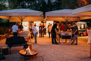Blick in den Biergarten mit Feuerschale und Tischkicker in der Dämmerung