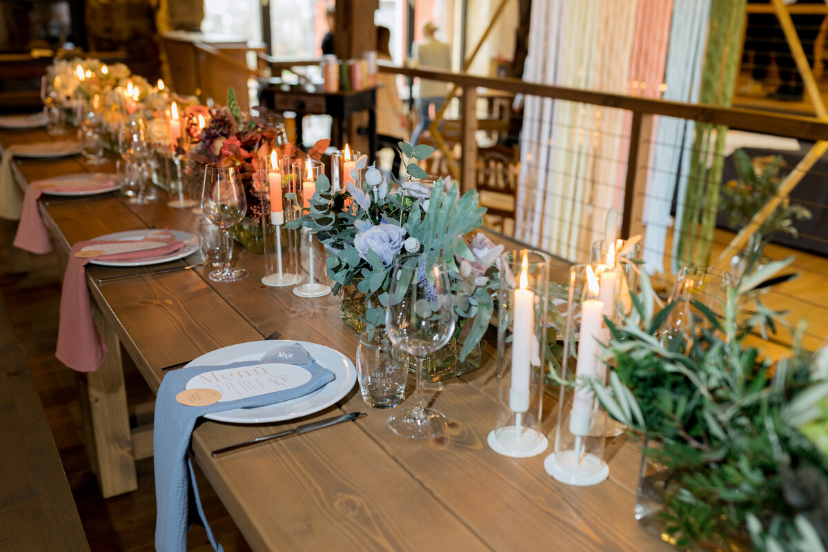 Festlich gedeckter Tisch mit Blumen, Kerzen und Menükarte für ein elegantes Abendessen oder eine Hochzeit.